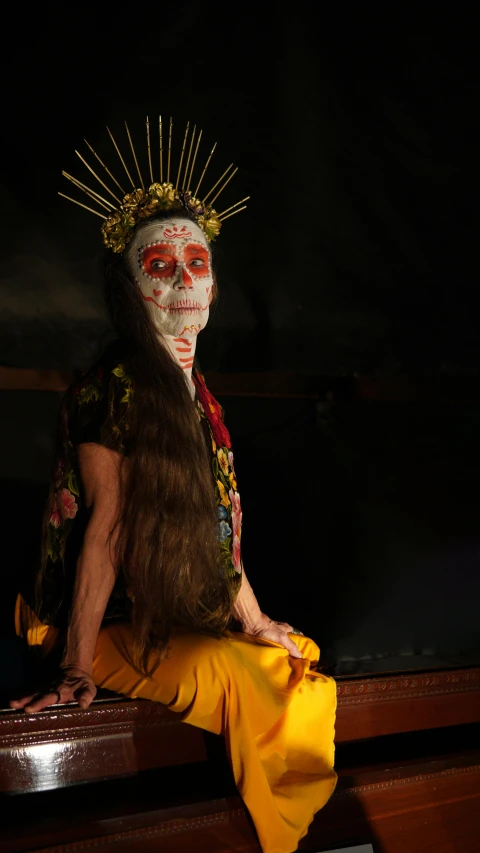 the skeleton woman with a long dark hair and painted face is posing for the camera