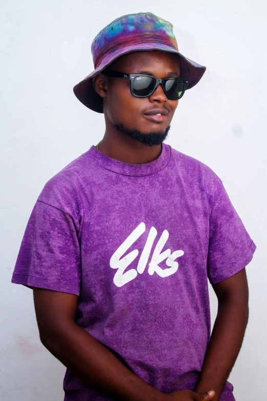 man in purple shirt and hat standing next to wall