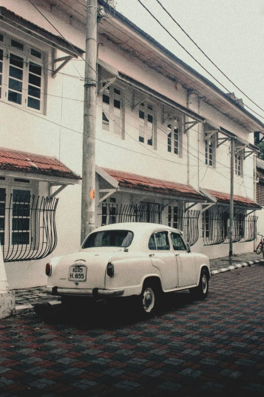 a white car driving down a street next to tall buildings