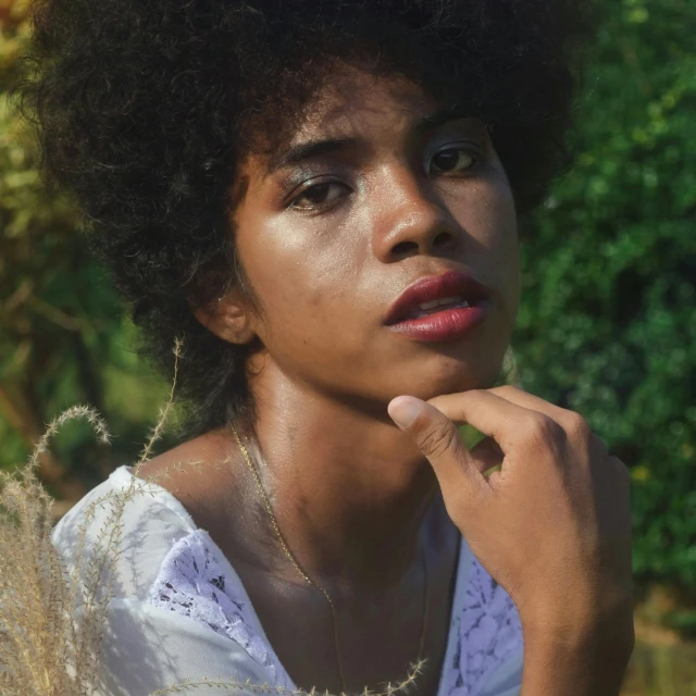 a woman with an afro holds her chin to her cheek