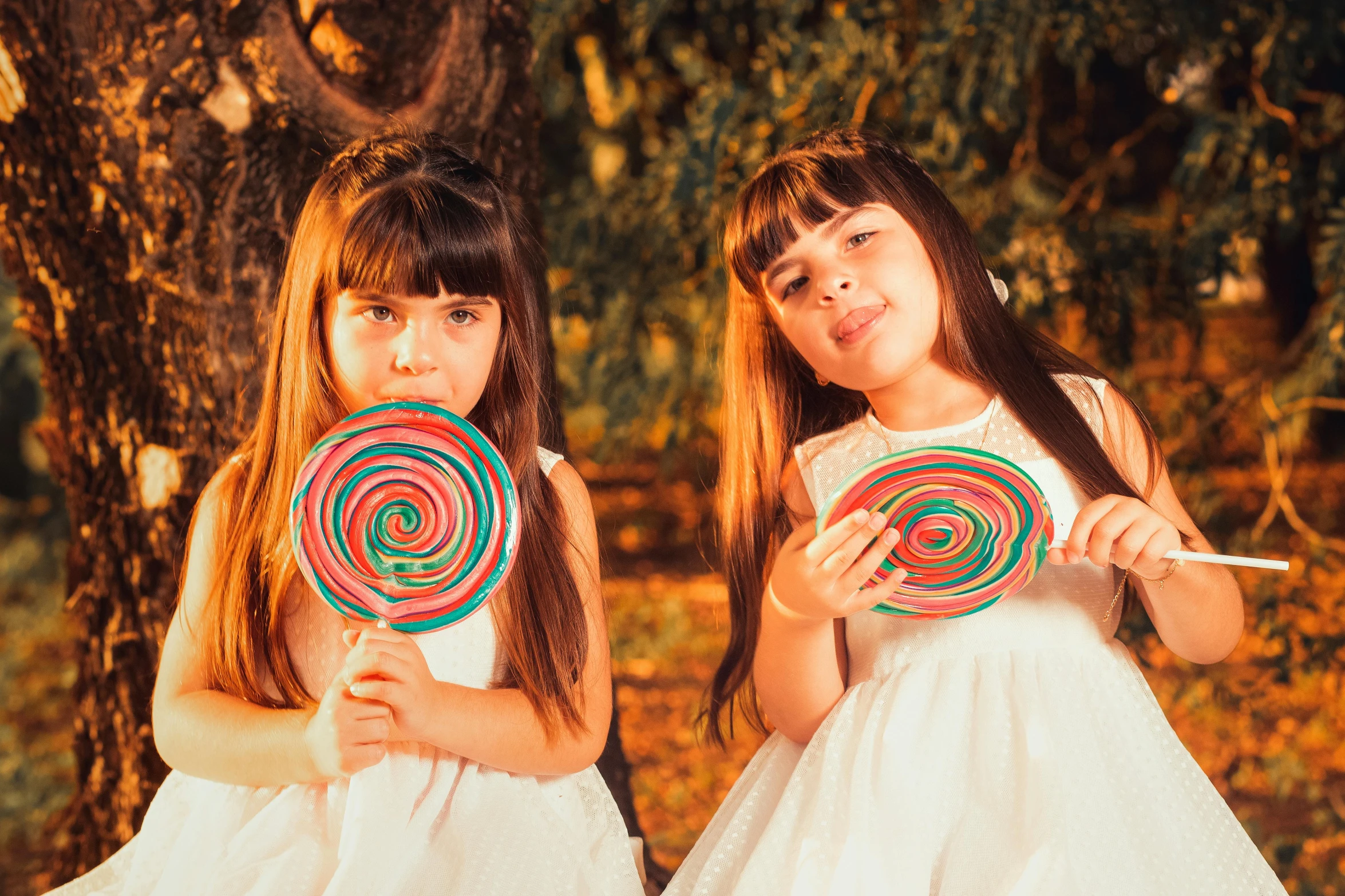 two little girls hold lollipops and smile