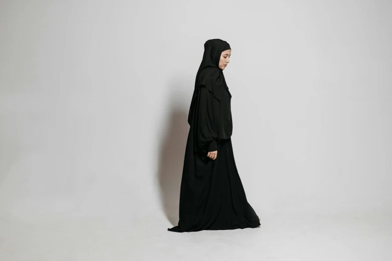 a woman is wearing a black outfit and standing on a white background