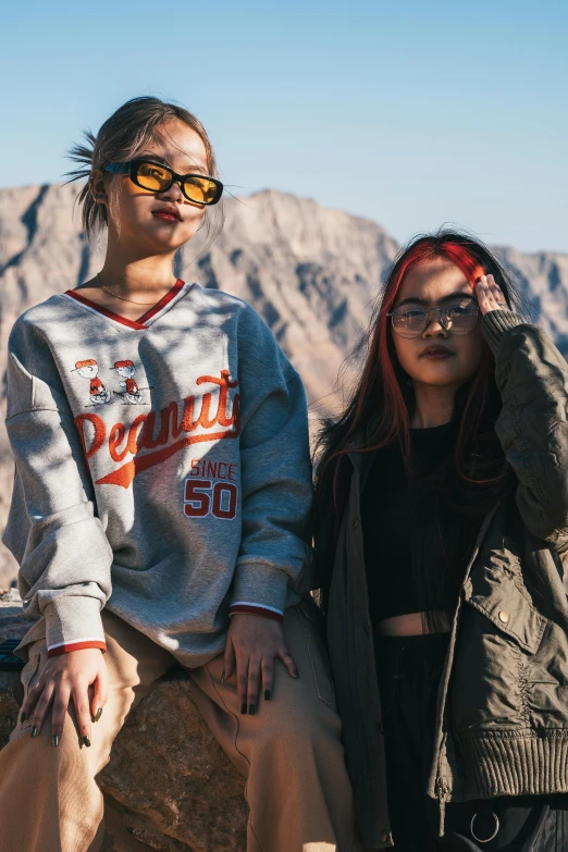 two young people sitting on top of a rock