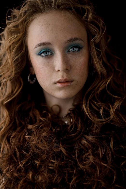 a woman with curly hair and a blue eyeliner