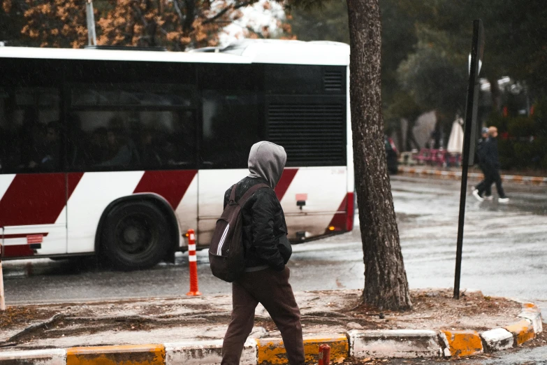 a person with a backpack is walking towards a bus on the road