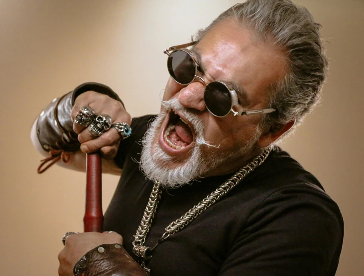 the man is holding an old fashion hammer and wearing round glasses