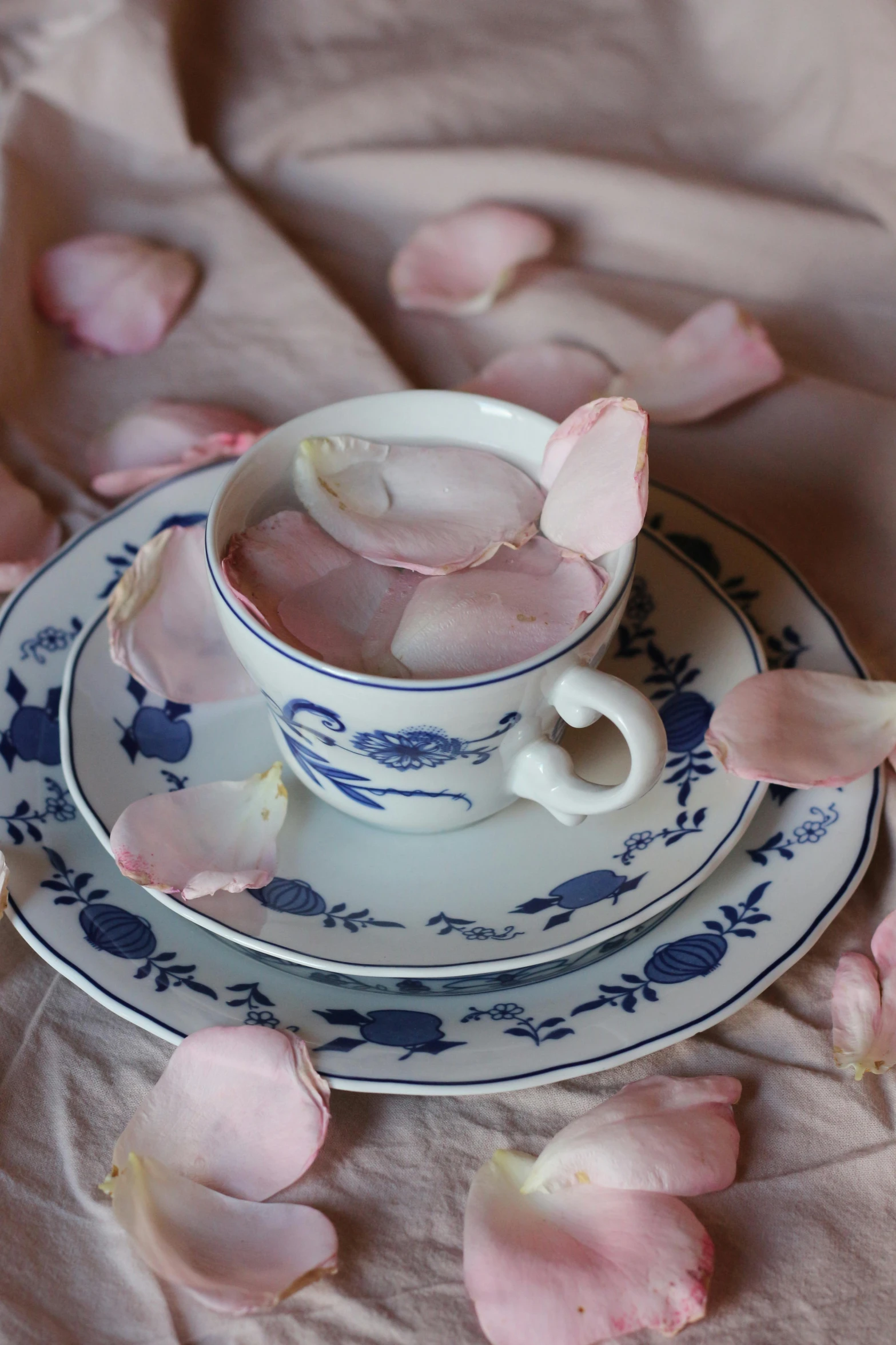 two cups and plates filled with pink petals