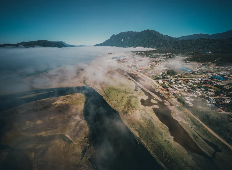 a valley filled with cloud covered hills next to a town