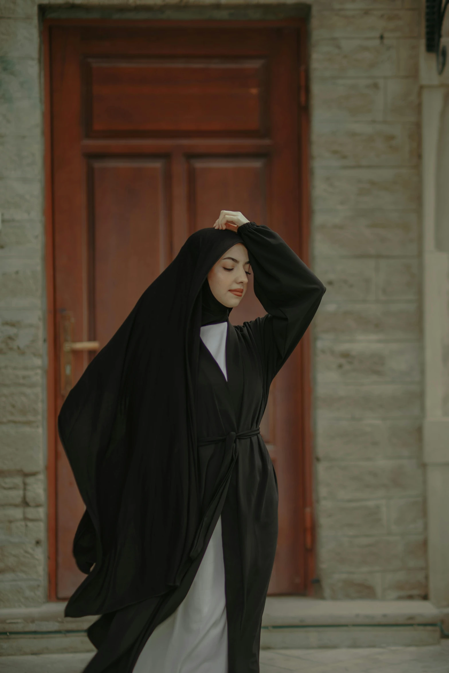 the woman in black is dressed in white and holds her head while wearing a long black shawl