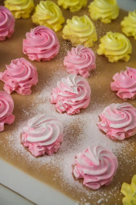 a bunch of pink and yellow frosted treats