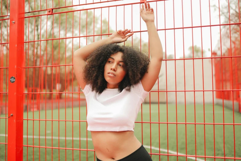 a woman is standing next to a fence