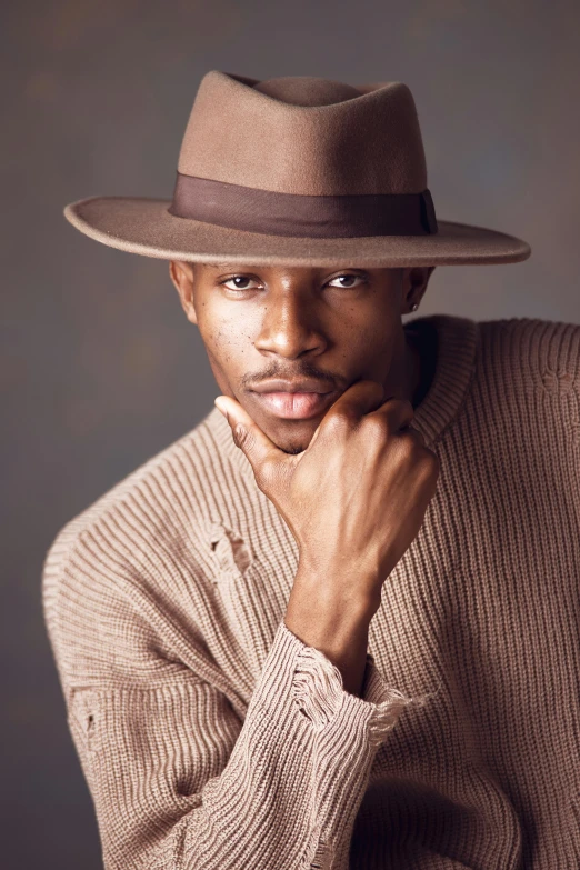 a man in a sweater and hat poses for a po