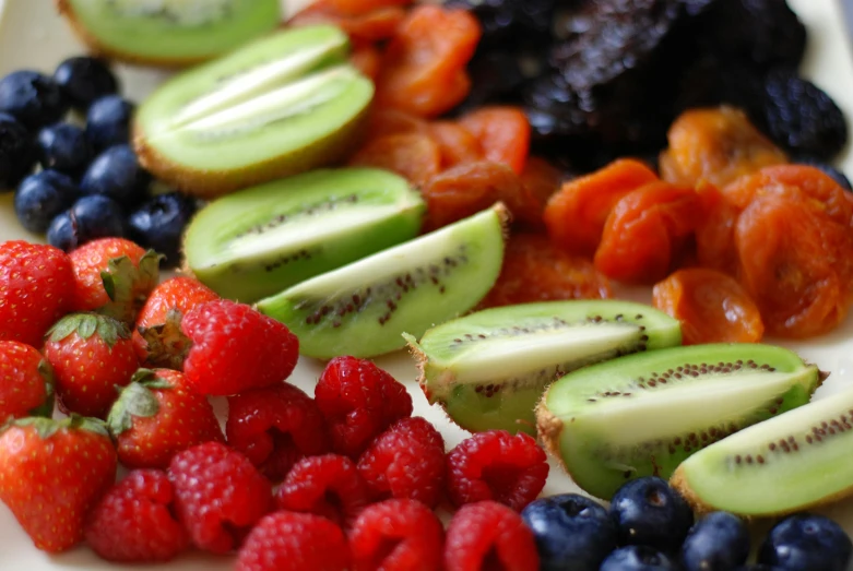 fruits are shown sitting on a plate with avocado, strawberries, raspberries and other fruit