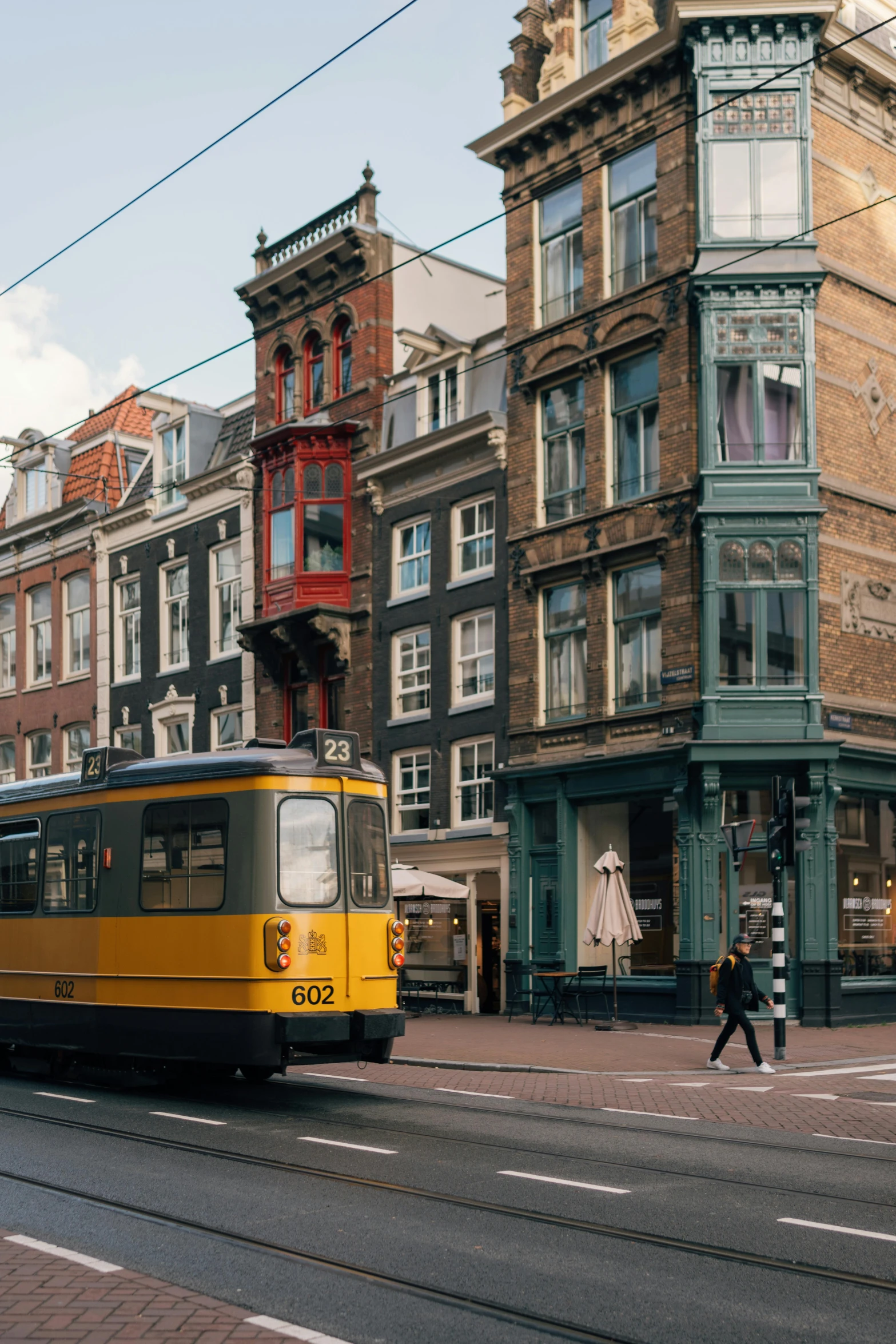 an old yellow and black tram some buildings and people