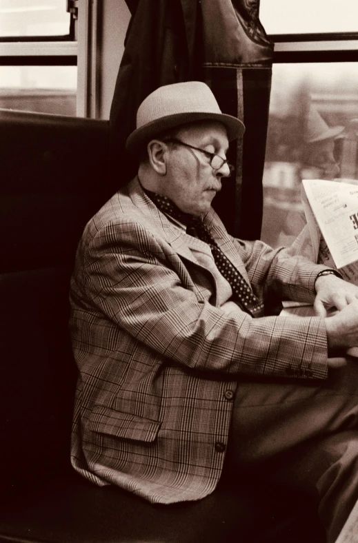 a man wearing a hat reading on a train