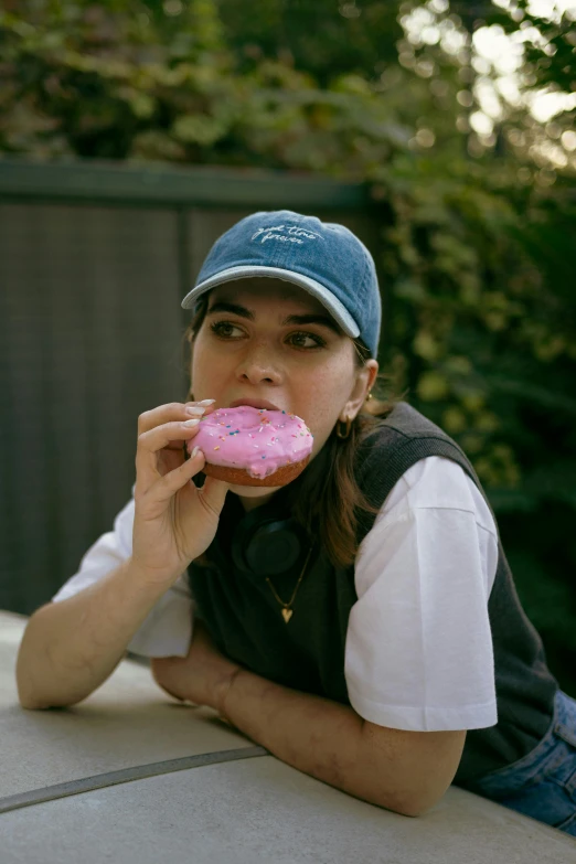 a woman laying down and eating a pink donut