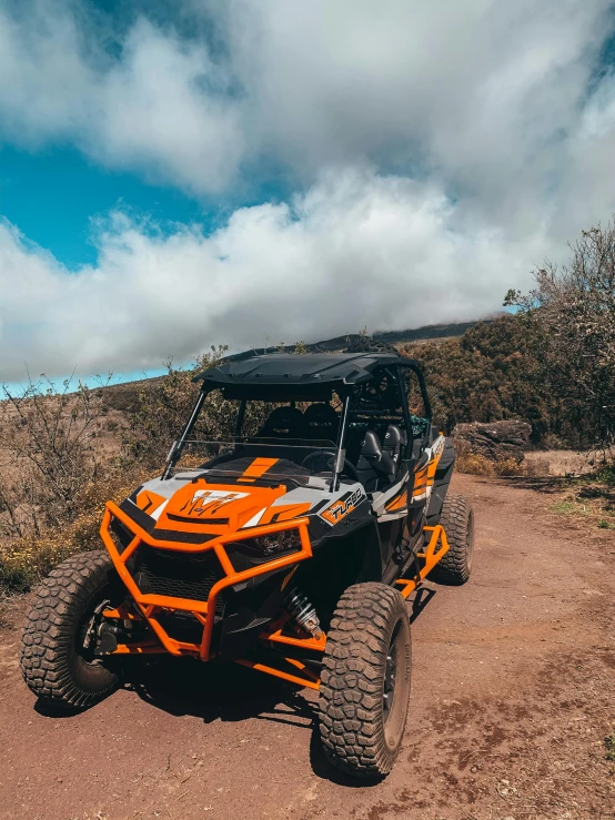 orange four - door uttool driving on dirt path