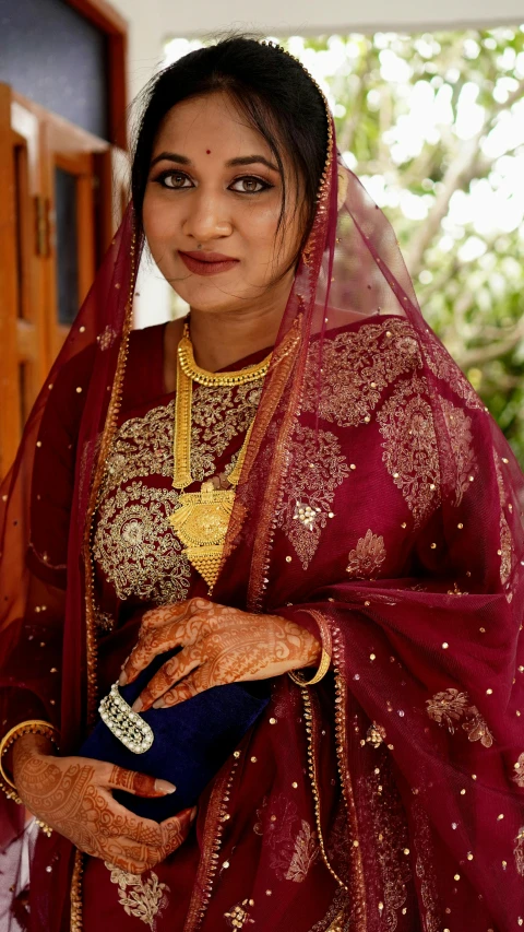 a indian woman is dressed in a red and gold sari