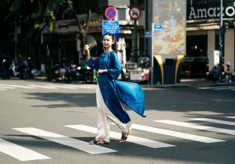 a woman crossing the road with her hands behind her head