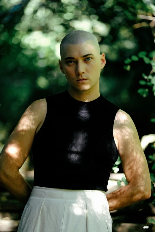 man with shaved head and black shirt in the sun