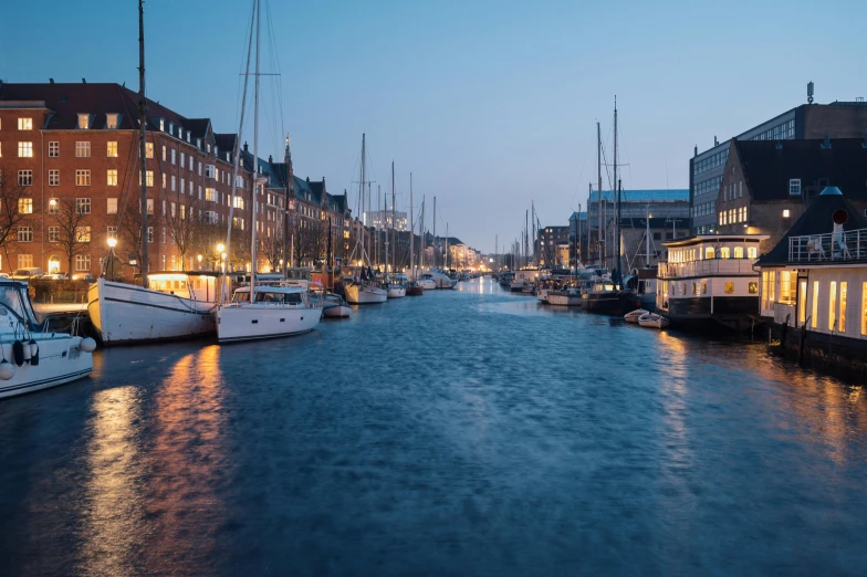 several sailboats are docked in a river at night