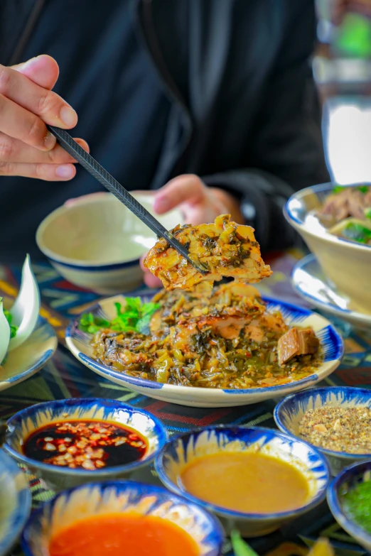 a person eating out of many dishes at the table