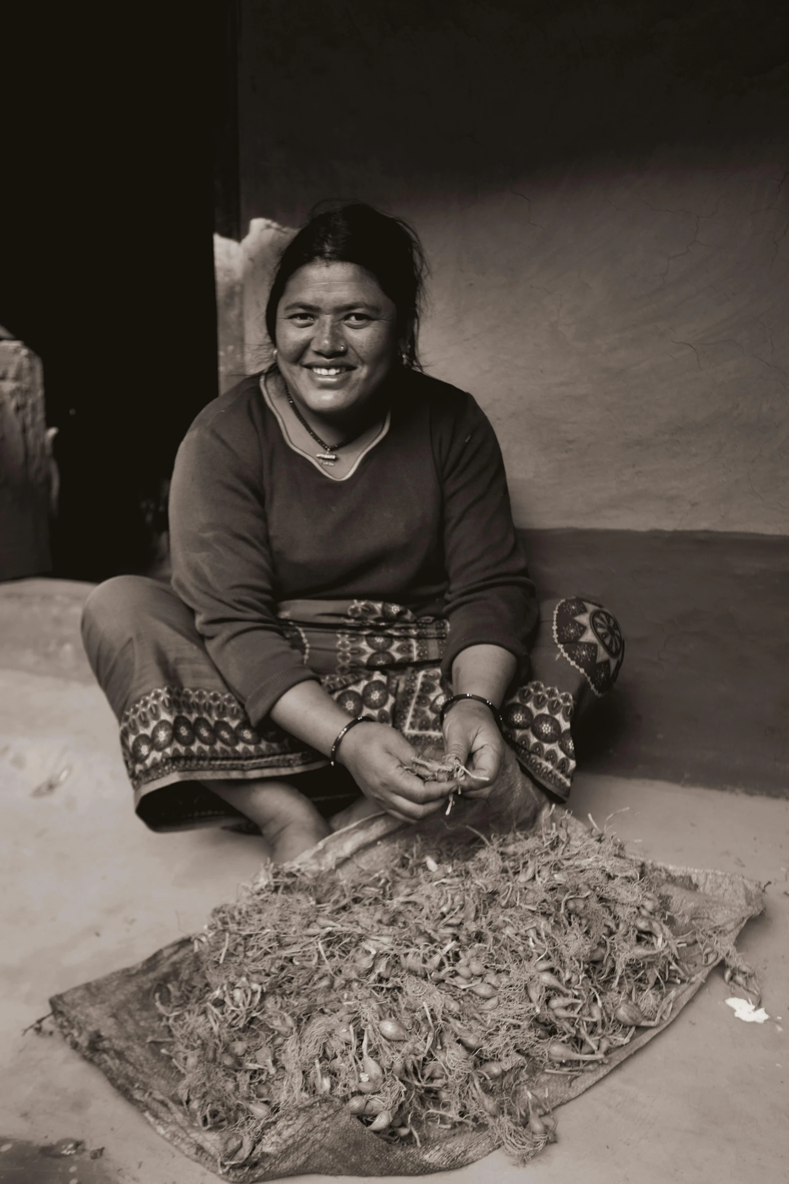 the woman smiles as she sits next to a rug