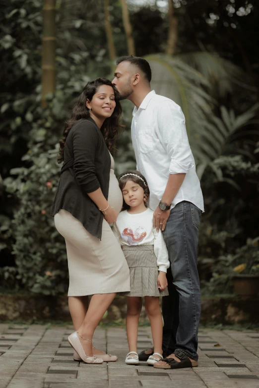 a family standing in front of lush trees