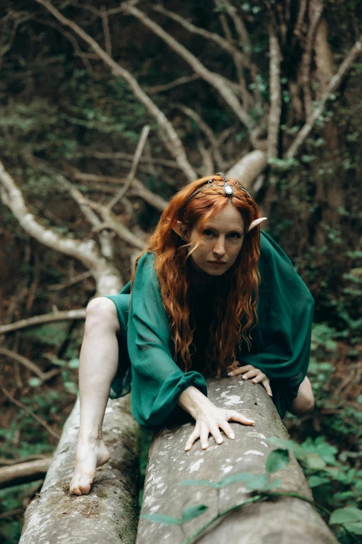 a woman in green dress sitting on a log