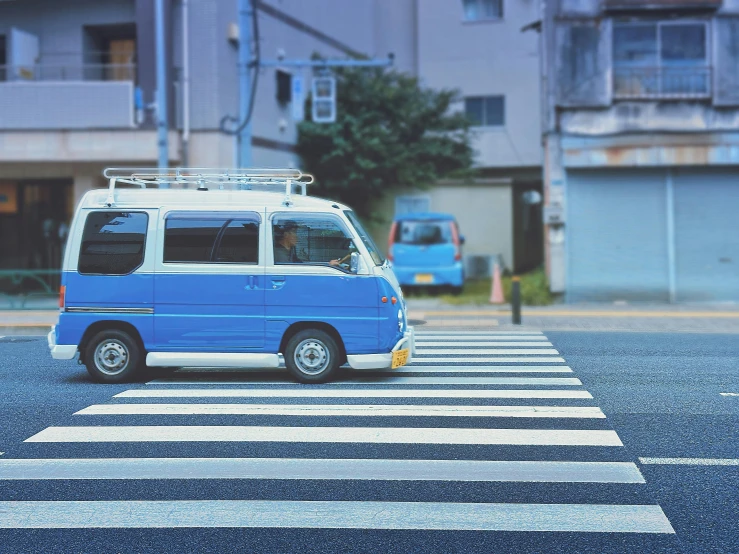 an suv parked at the end of a ze crossing in front of buildings