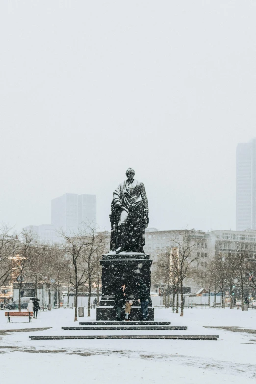 a statue that is in the snow next to trees