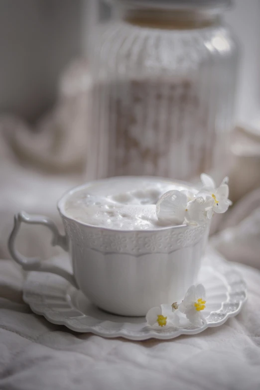 a mug on a saucer with a white flower and a jar