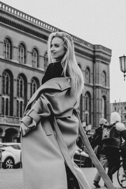 a woman wearing a large coat and heels is walking in the street