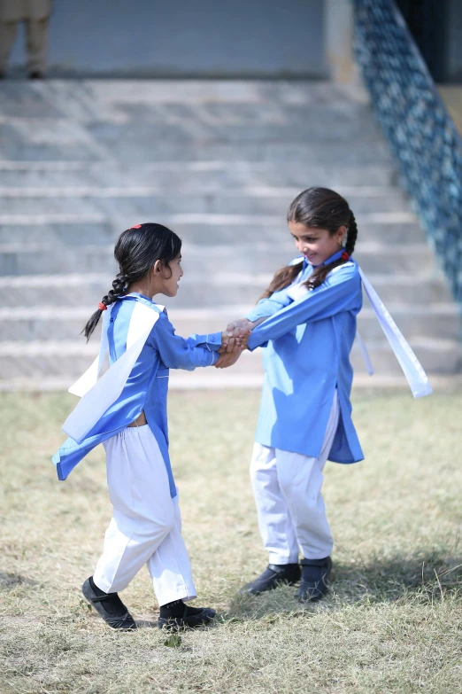 two girls dressed in blue and white holding hands