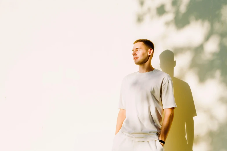 a man standing in front of a wall next to a tree