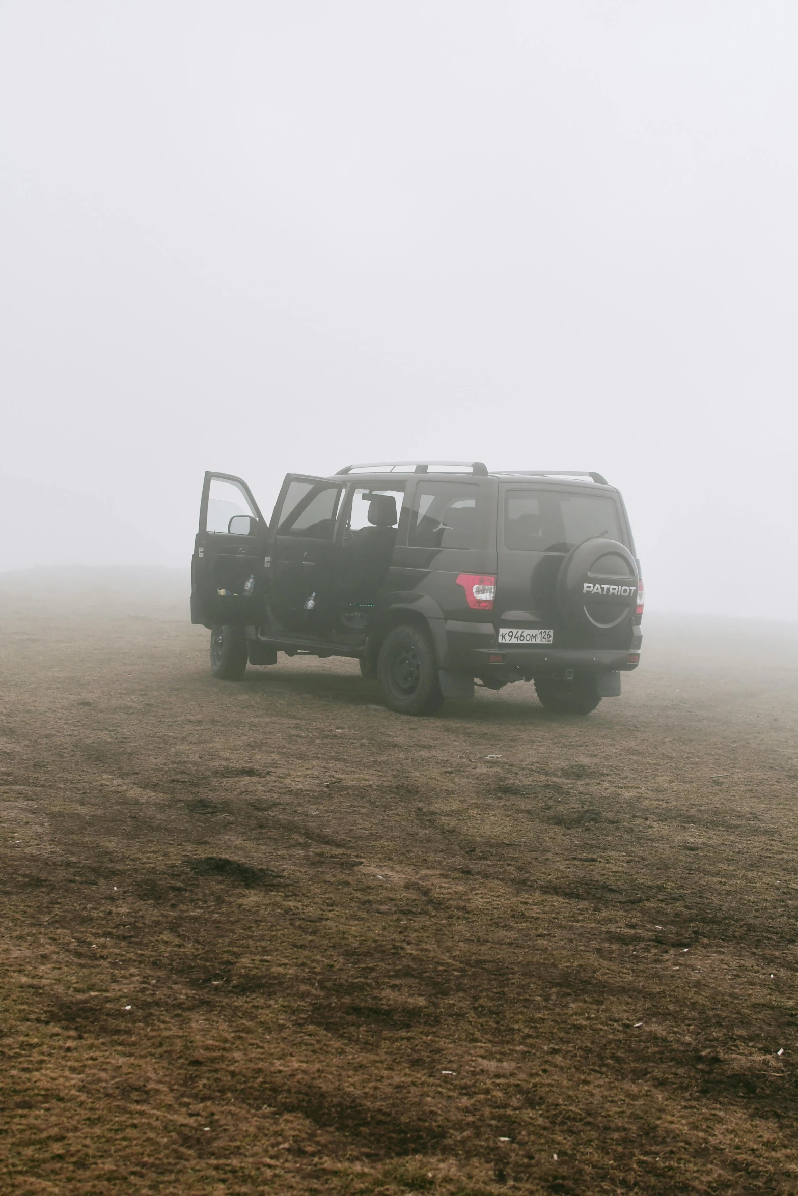 two vehicles traveling across a field in the fog