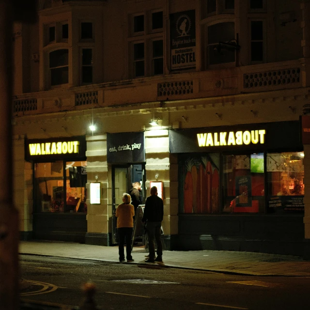 three people stand in front of a store at night