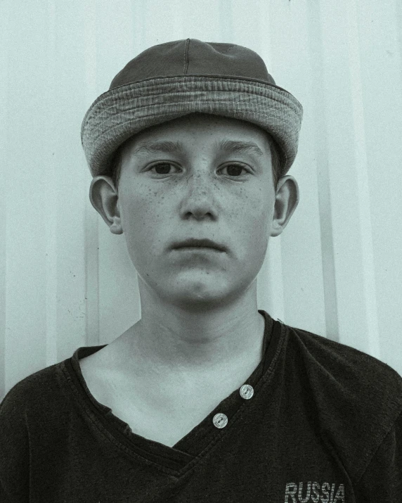 a boy poses for the camera, wearing a hat