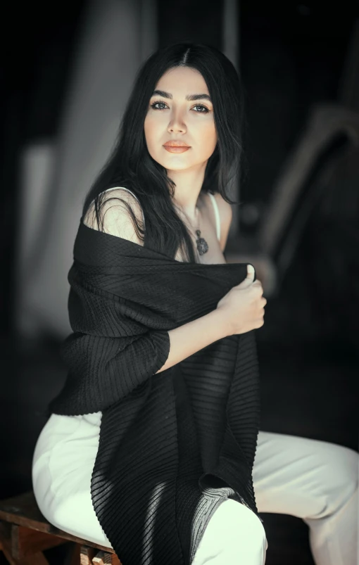 an asian woman wearing a black sweater and white pants