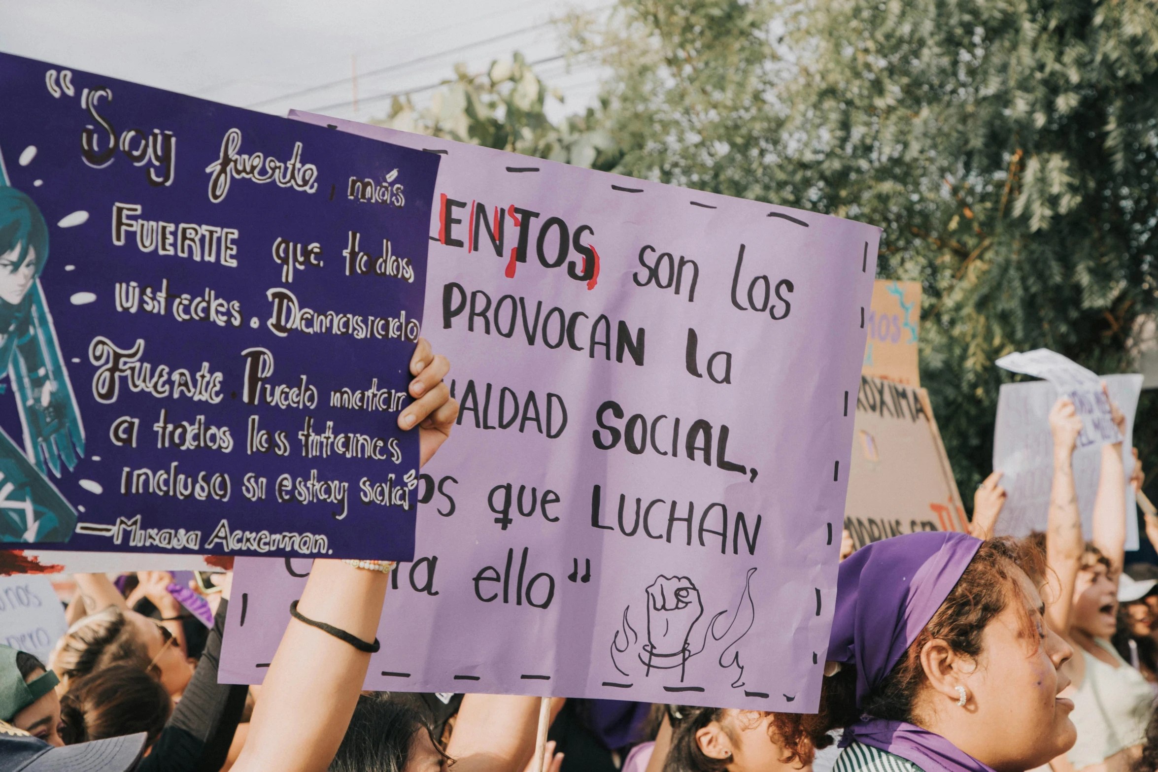 a group of people with signs and some trees