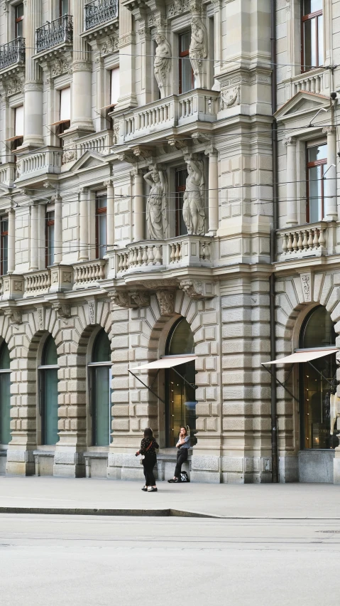 three people walking down a sidewalk near a tall building