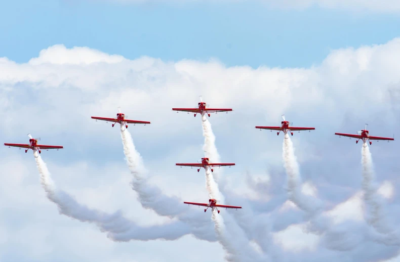 six airplanes are performing stunts and trailing smoke