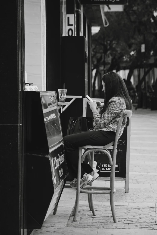 woman sitting on chair reading newspaper at outdoor stand