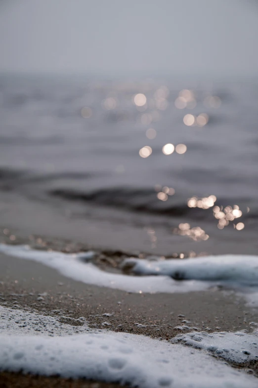 ocean foaming and tide on beach with white sand