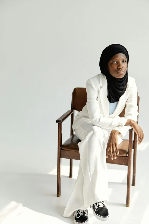 the woman sitting is wearing a white suit and black shoes