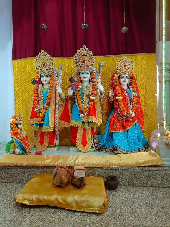 some statues with people dressed as goddesss and the man in a blue outfit