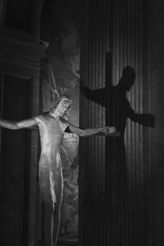 man casting a shadow in a darkened area with an abstract sculpture