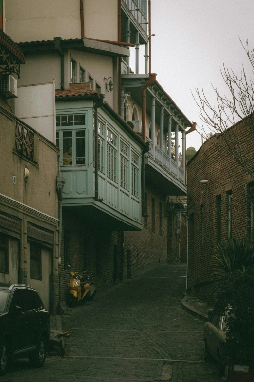 old brick buildings with balconies are on the opposite sides of the alleyway