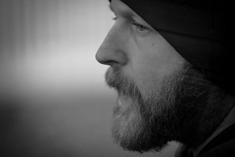 a man with a beard, wearing a beanie and looking off to the side