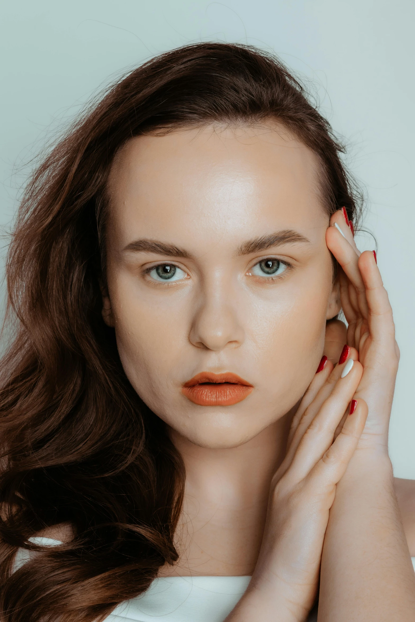 a close up view of a model wearing red nails and bright orange lipstick